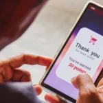 21 Best Loyalty Programmes 2025: Man holding phone with a points system