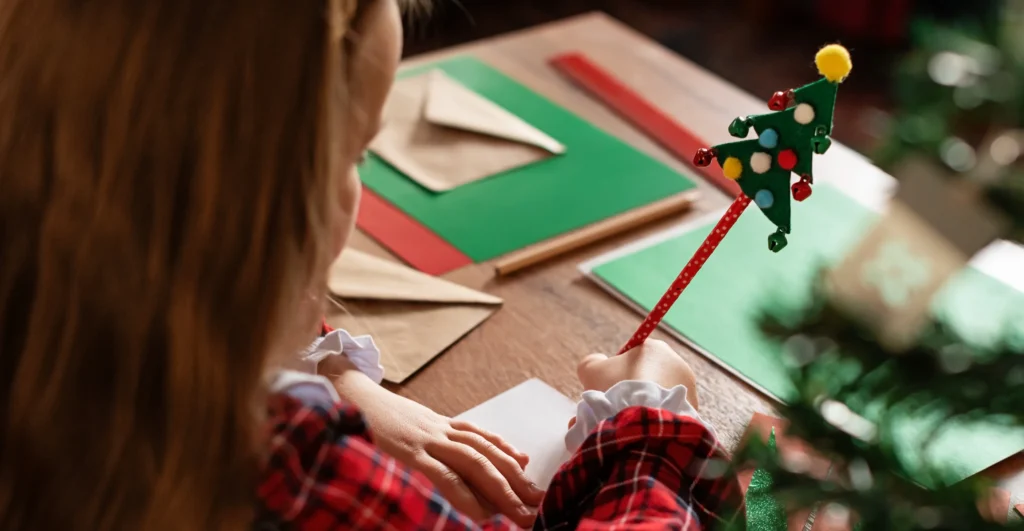 Joy with Royal Mail: child writing a Christmas card with Christmas tree pen