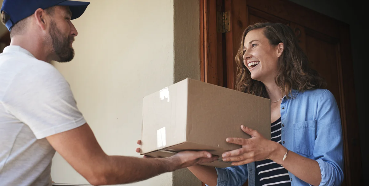 Digital vs Physical: woman happily receiving parcel at front door