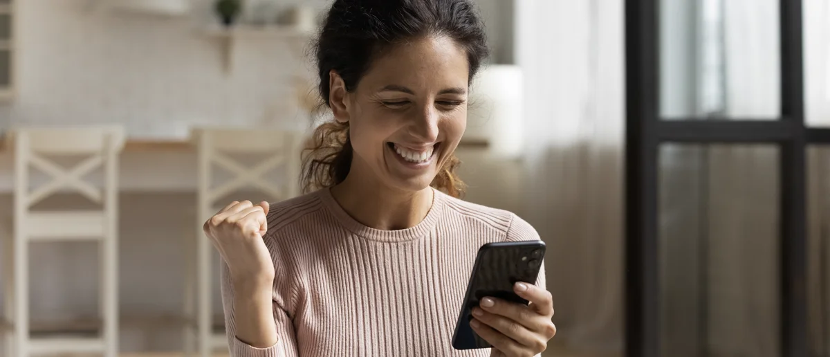 Instant Digital Rewards: Lady on her phone celebrating her digital instant win